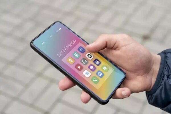 Человек держит смартфон с иконками социальных сетей на экране.