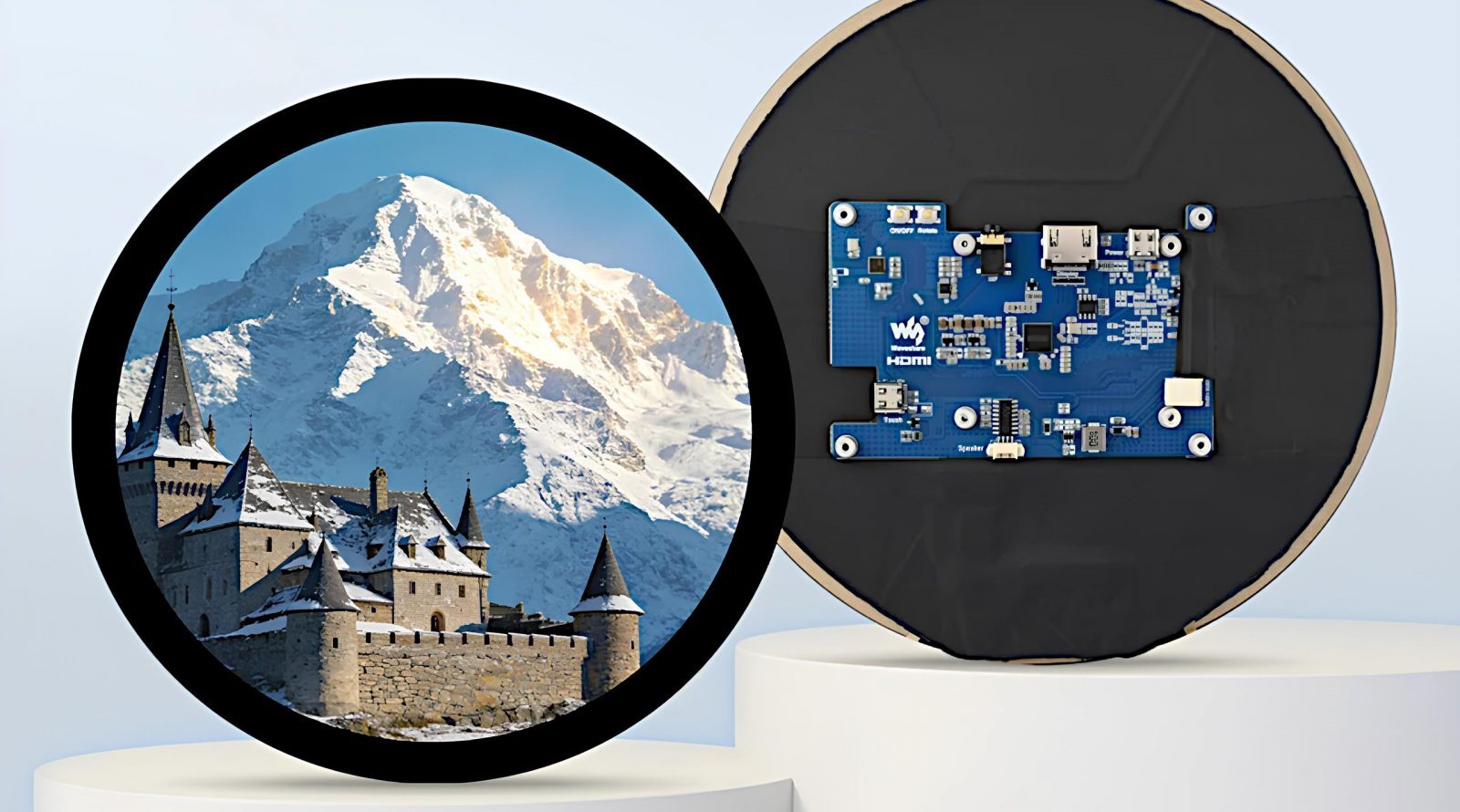 Круглый экран с изображением замка и горы, рядом электронная плата.