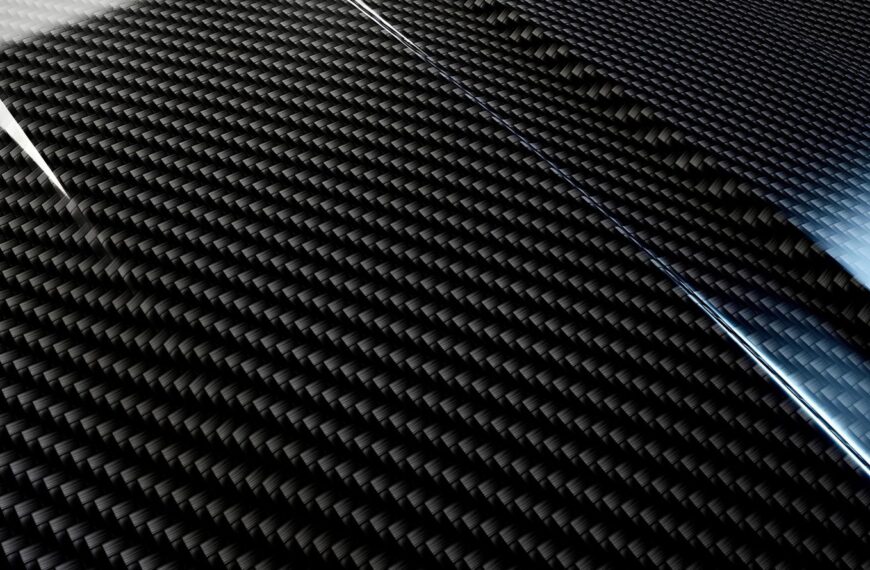 Черный углеродное волокно с текстурой плетения, отражающий свет.