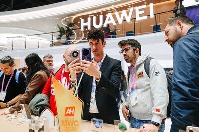 Люди на стенде Huawei тестируют смартфоны на выставке.