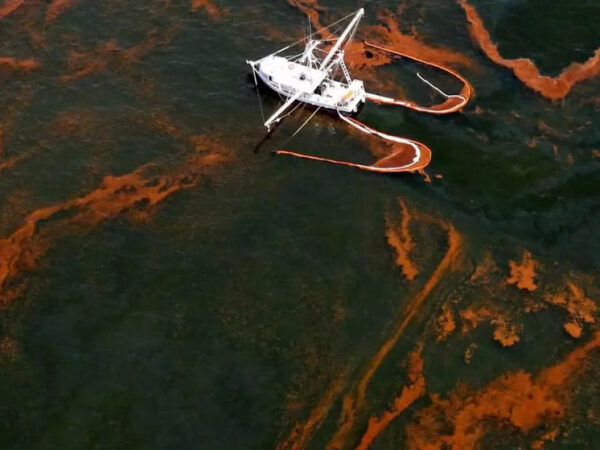 Лодка на фоне нефтяного разлива в море, аварийная экологическая ситуация.