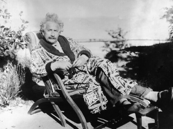 Мужчина в халате отдыхает на шезлонге на природе.