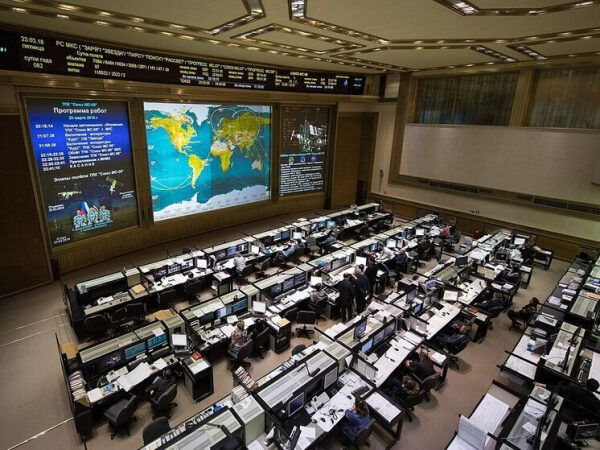 Центр управления полетами, сотрудники за компьютерами, карты на экранах.