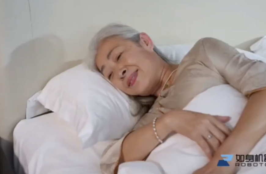 Пожилая женщина отдыхает в постели с улыбкой, лежа на белых подушках.