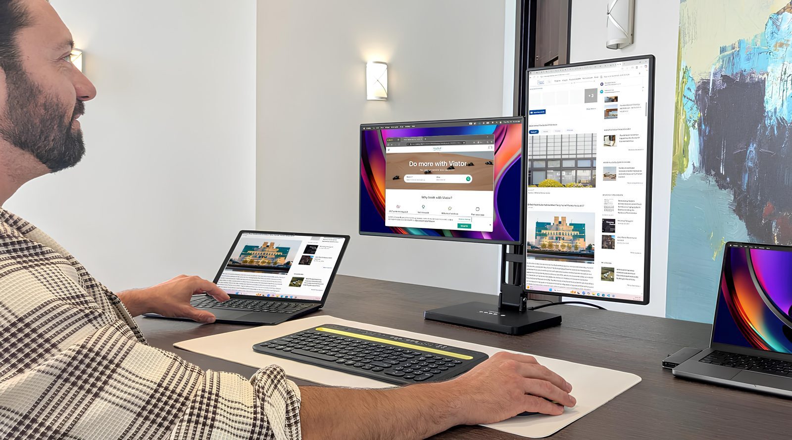 Мужчина работает за столом с несколькими экранами и ноутбуками в офисе.