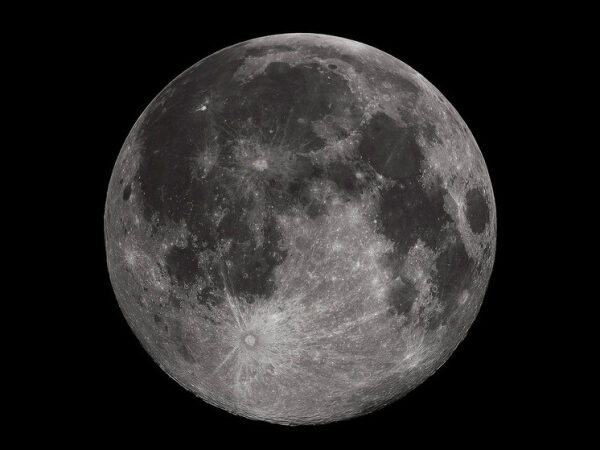 Полная луна на черном небе с отчетливыми кратерами и деталями поверхности.