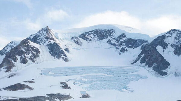 Заснеженные горы и ледник под голубым небом.