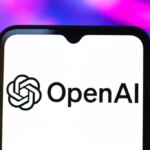 Логотип OpenAI на экране смартфона, фон яркий и размыт.