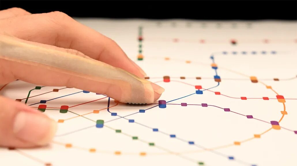 указательный палец, на который надето устройство, похожее на пластырь, чтобы чувствовать цветные точки на странице