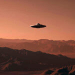 Летающая тарелка над пустынными горами на закате с красными оттенками неба.