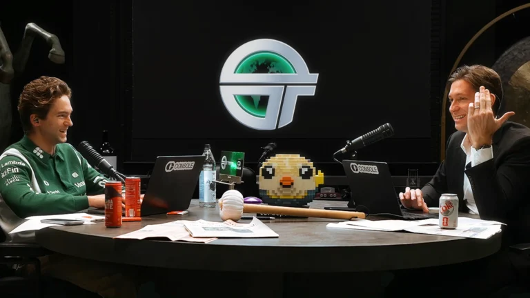 Двое мужчин за столом с ноутбуками и микрофонами, фон с логотипом.