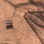 Крошечный микрочип на фоне монеты, демонстрирующий миниатюризацию технологий.