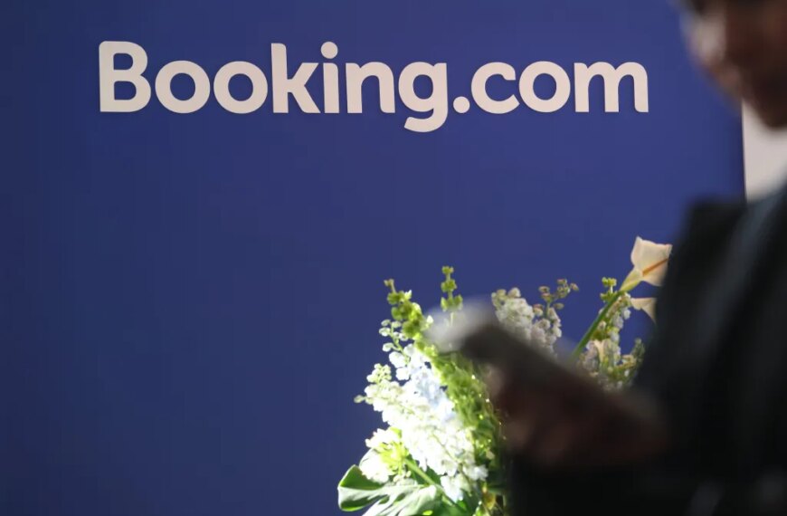 Логотип Booking.com на синем фоне с цветами на переднем плане.