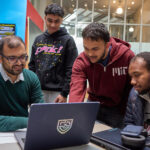 Студенты работают за ноутбуком, обсудив проект в современном пространстве.