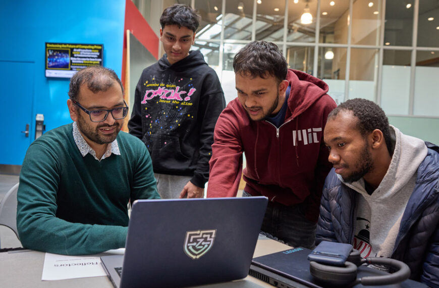 Студенты работают за ноутбуком, обсудив проект в современном пространстве.