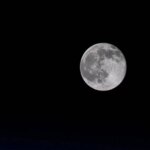 Полнолуние на ночном небе, яркий свет Луны в темноте, астрономия и природа.