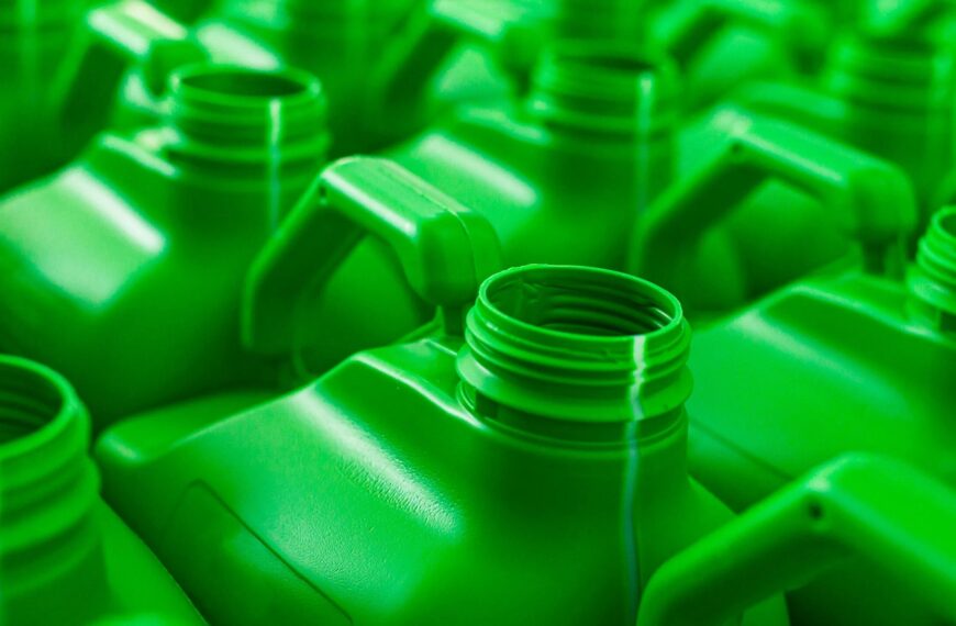 Ряд зеленых пластиковых канистр с ручками, крупный план. Экологичная тара для жидкости.