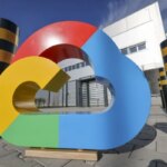 Красочный логотип Google Cloud на фоне офисного здания и столбов на улице.