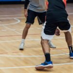 Баскетболисты играют в зале, один делает дриблинг.