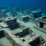 Подводный древний город с руинами и лестницами на морском дне.