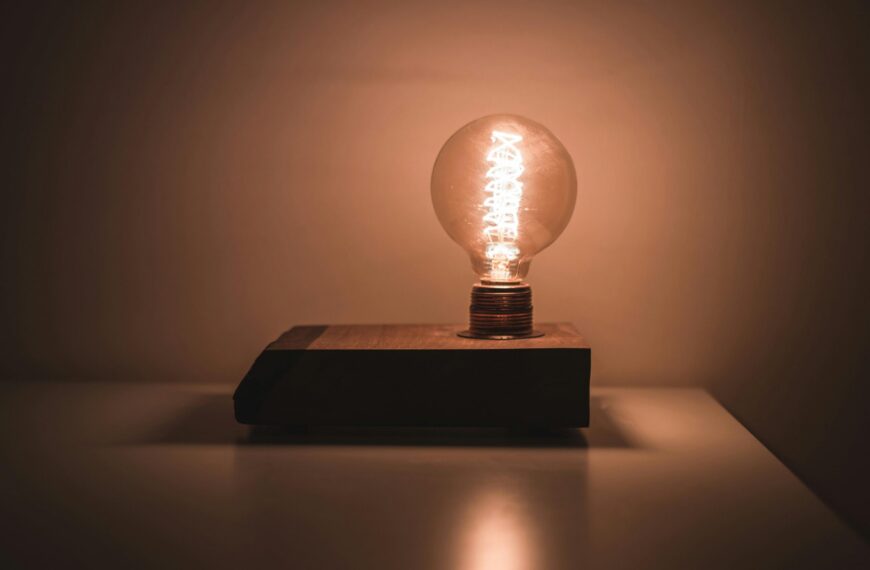 Лампочка на деревянной основе, освещающая темное помещение. Винтажный стиль, теплое свечение.