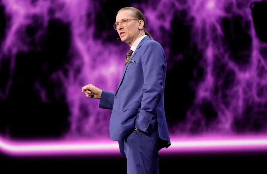 Человек в синем костюме на фоне фиолетовых узоров.