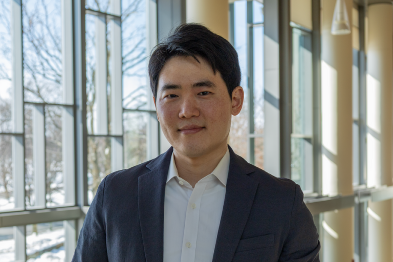 Мужчина в костюме на фоне современного стеклянного интерьера.