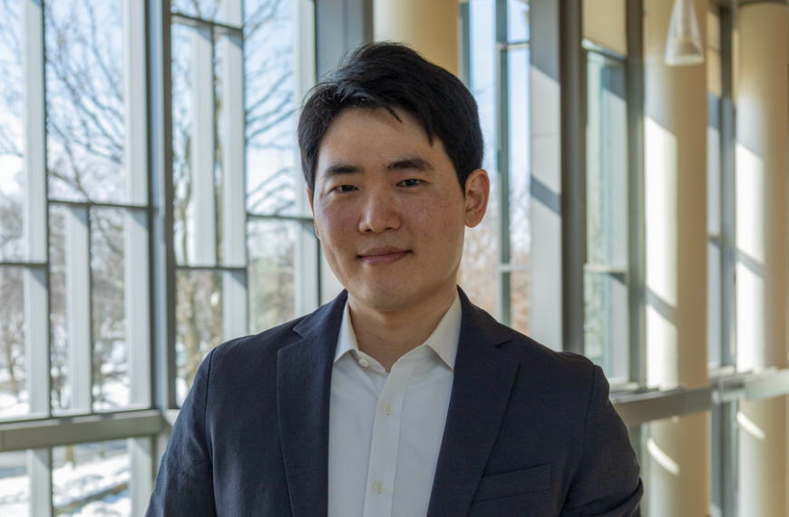 Мужчина в костюме на фоне современного стеклянного интерьера.