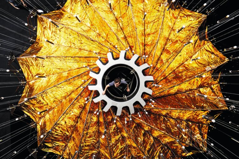 Человек внутри солнечного паруса спутника с золотыми лепестками.