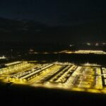 Ночное фото освещенного дата-центра с высоты, видны здания и освещение.