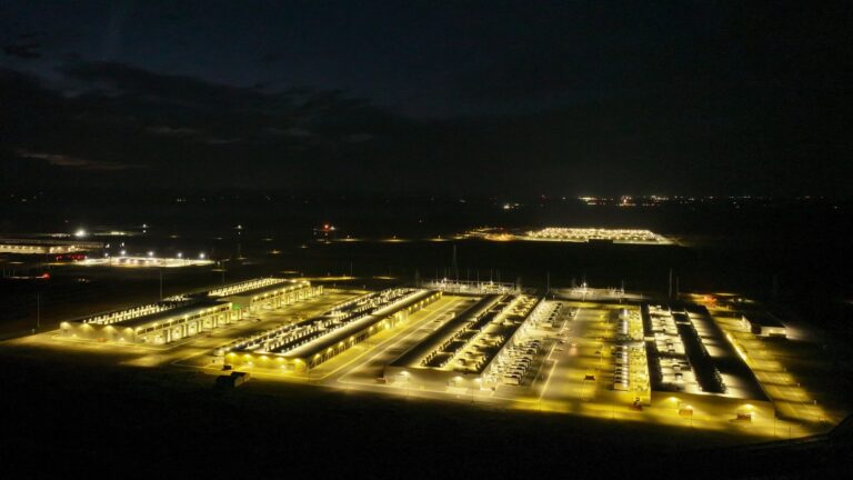 Ночное фото освещенного дата-центра с высоты, видны здания и освещение.