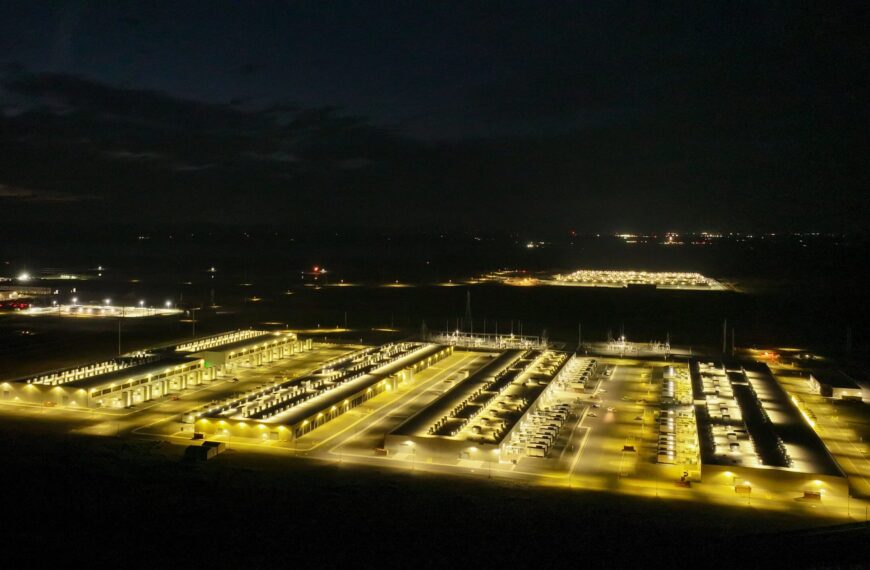 Ночное фото освещенного дата-центра с высоты, видны здания и освещение.