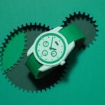 Зеленые наручные часы на фоне с зубчатыми колесами, стильный дизайн аксессуара.