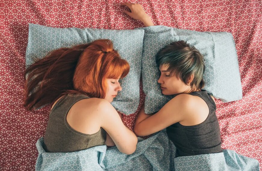 Две женщины отдыхают на кровати с цветным покрывалом, вид сверху.