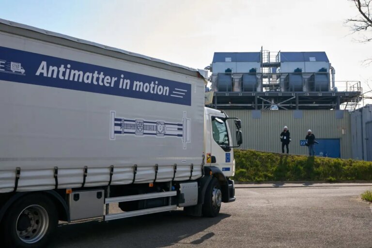 Грузовик с надписью "Antimatter in motion" на заводской территории, антиматерия в движении.