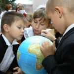 Дети изучают глобус в классе, школьный урок географии.