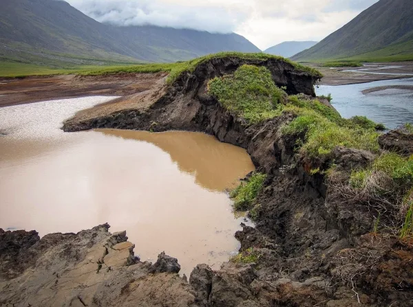 Насыпь обрушившейся земли, окруженная мутной водой.