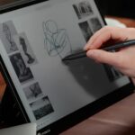 Человек рисует на электронном планшете стилусом. Эскизы статуй на экране.