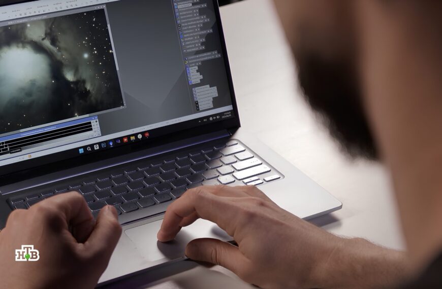 Мужчина работает на ноутбуке, редактируя изображение туманности в графическом редакторе.