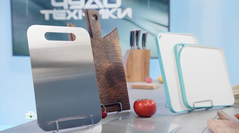 Разнообразные разделочные доски на кухонном столе, рядом помидоры.