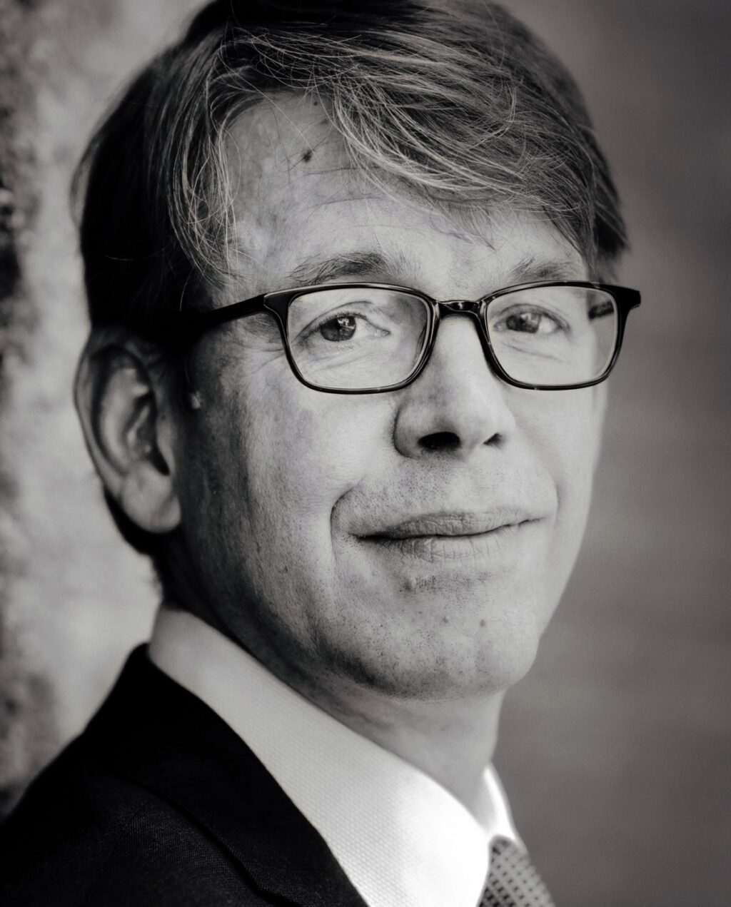 Портрет белого мужчины в очках и со светлыми волосами, в профиль.