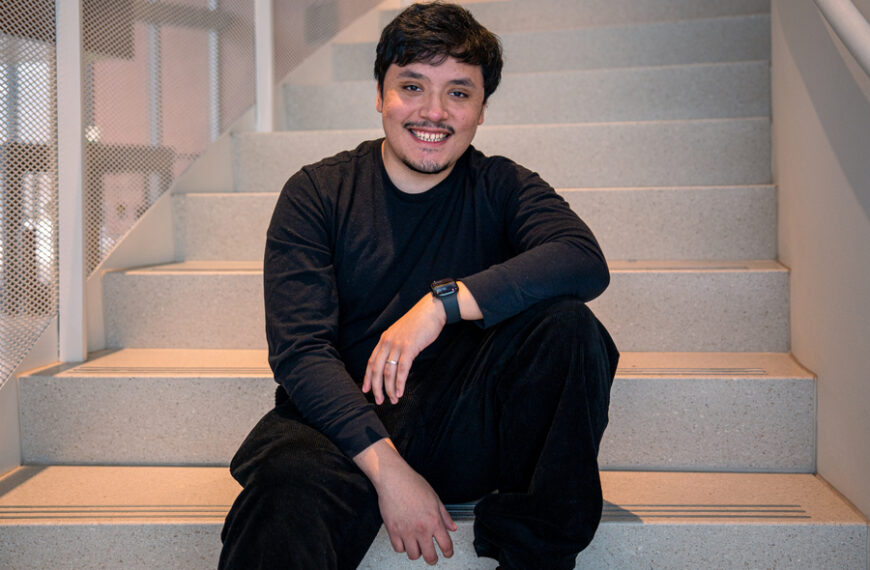 Человек в чёрном сидит на ступеньках, видны стильные часы на руке.