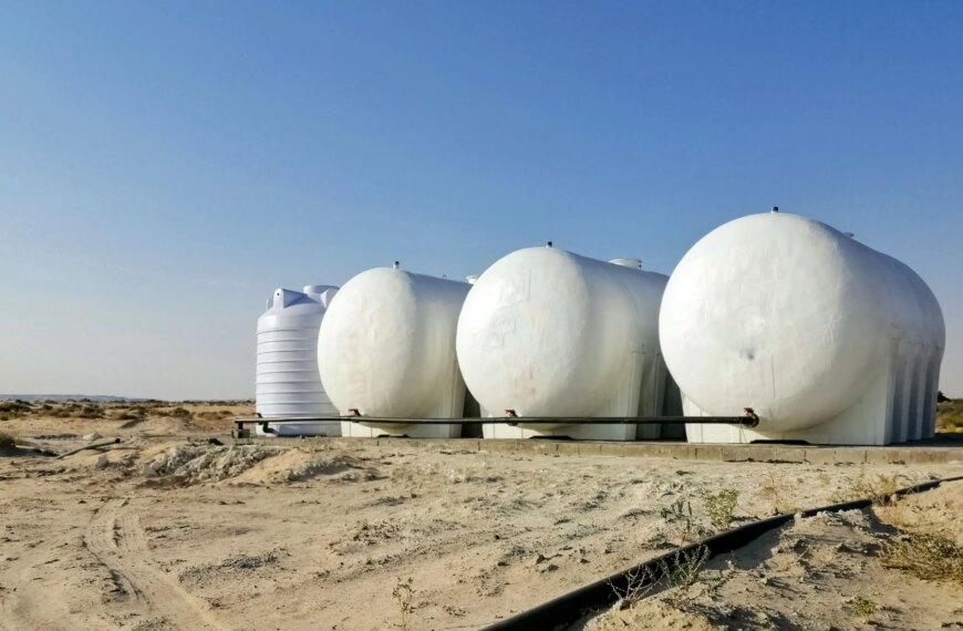 Белые резервуары для хранения воды на фоне пустынного пейзажа.