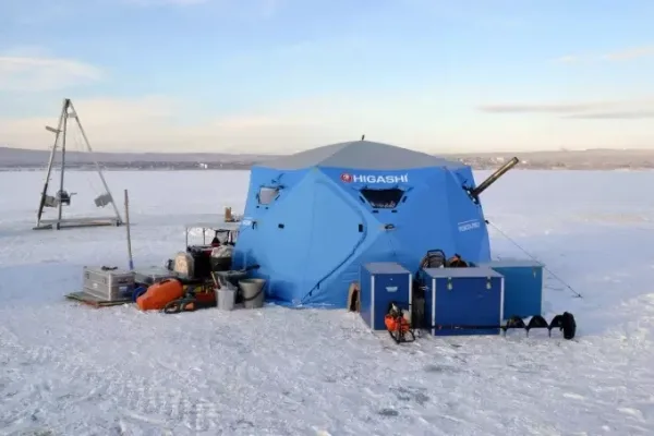 Палатка Higashi на льду с оборудованием для зимней рыбалки.