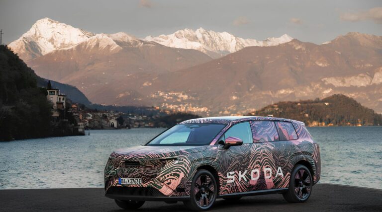 Автомобиль Skoda с камуфляжем на фоне горного озера и снежных вершин.