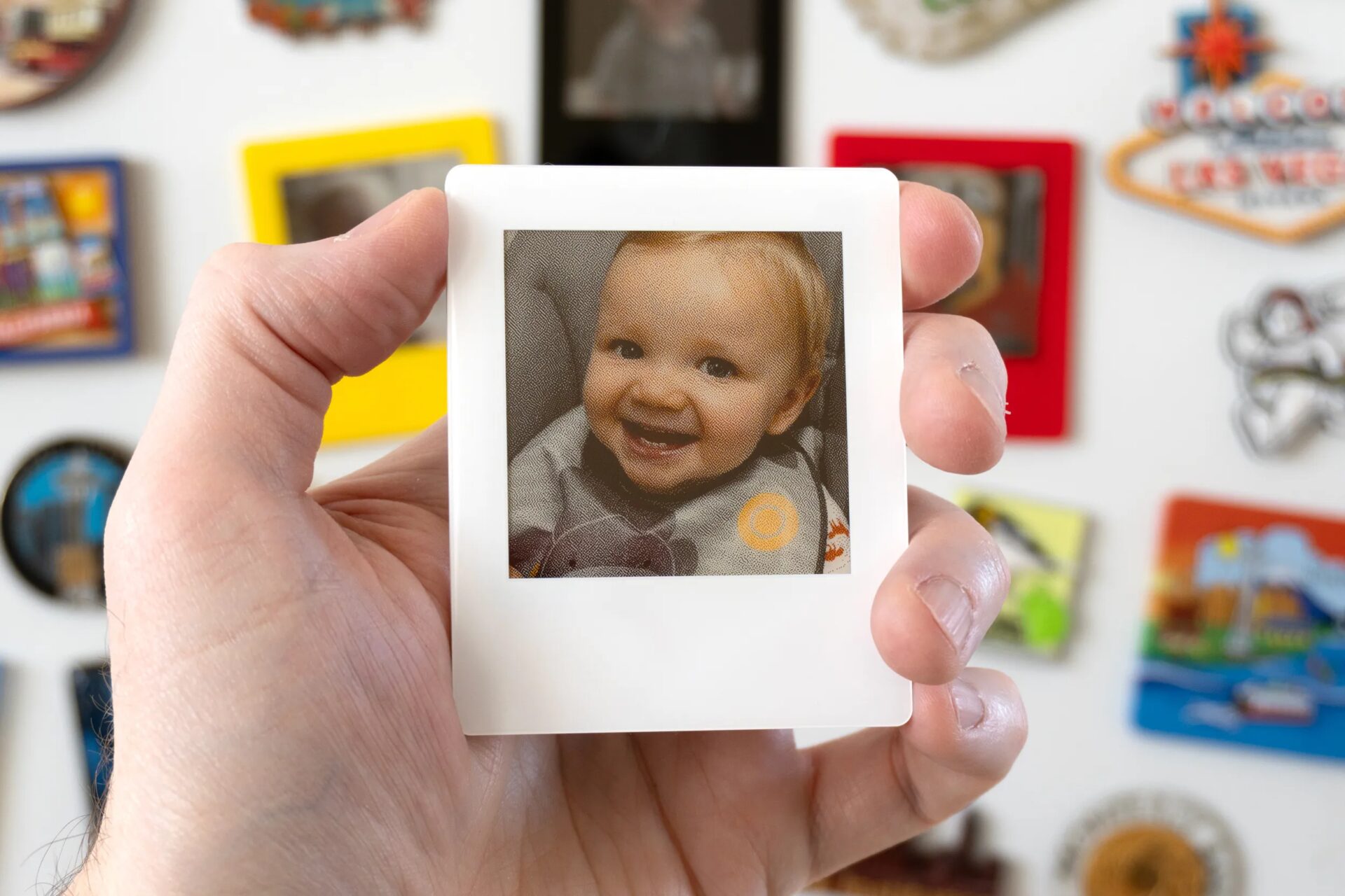 Человек держит в одной руке фоторамку VidaBay Snap с изображением маленького ребенка в нагруднике.