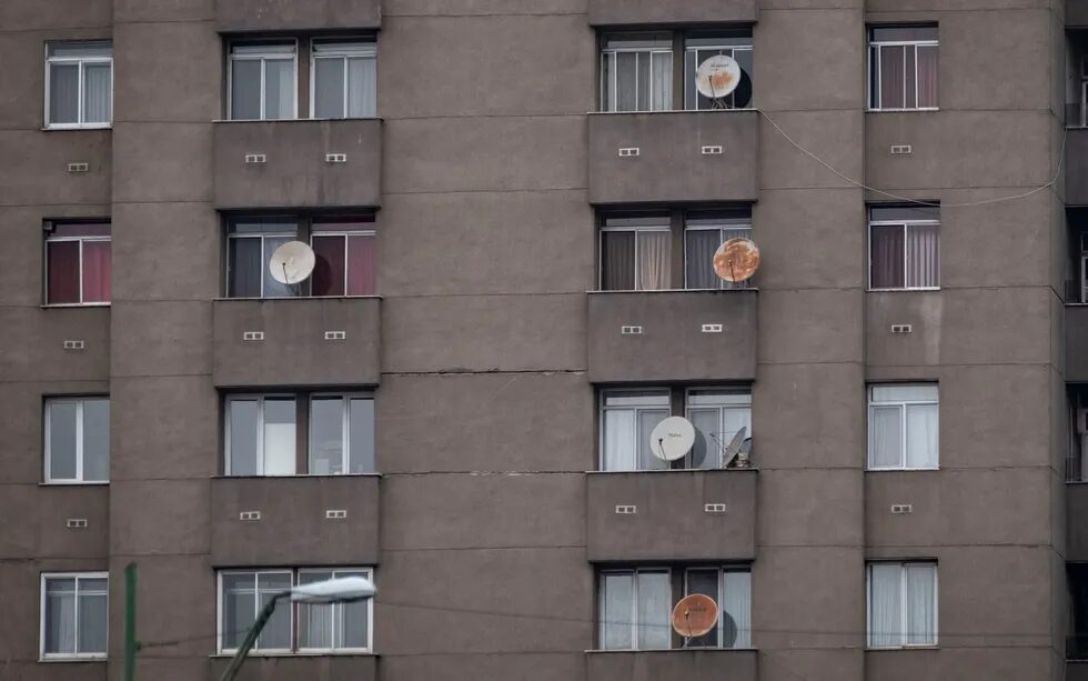 Фотография спутниковых антенн, украшающих стену многоквартирного дома.