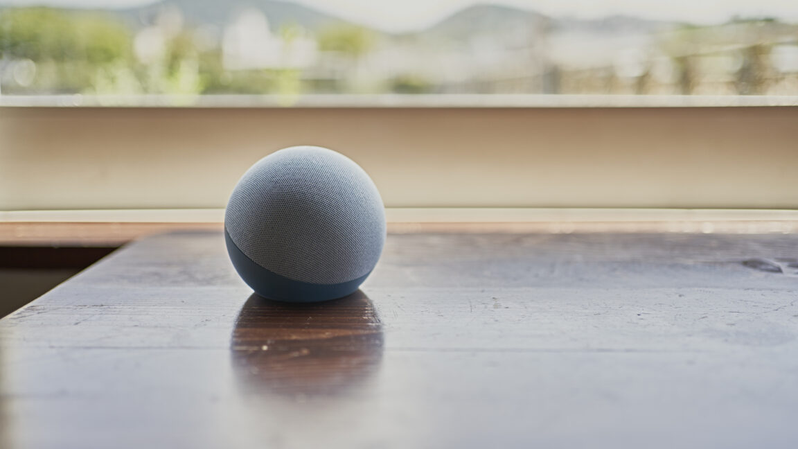 Умная колонка Amazon Echo Dot на столе у окна.
