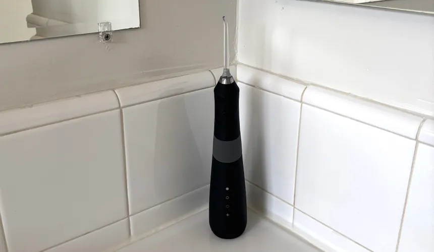 Черный ирригатор для полости рта Burst Water Flosser на белой столешнице в ванной комнате.