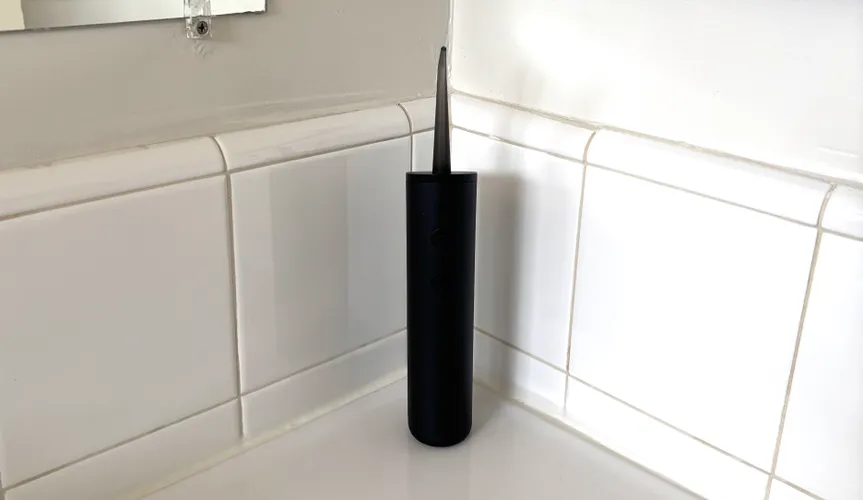 Черный ирригатор Quip Water Flosser на белой столешнице.